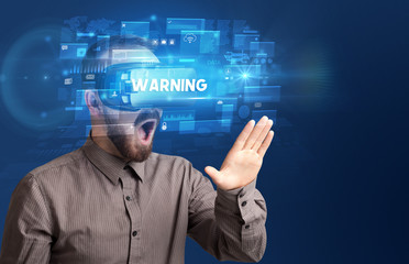 Businessman looking through Virtual Reality glasses with WARNING inscription, innovative security concept