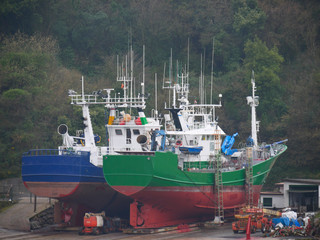 Two green and blue fishing boats in dry dock