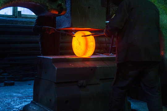 close-up picture of hot steel manual forging process with big mechanical hammer machine