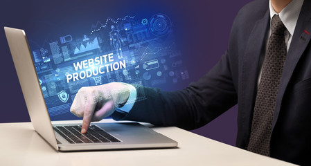 Businessman working on laptop with WEBSITE PRODUCTION inscription, cyber technology concept