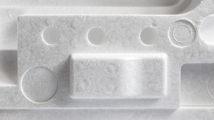 Polystyrene or styrofoam padding for product packaging. Detail of styrene foam plastic box close-up.