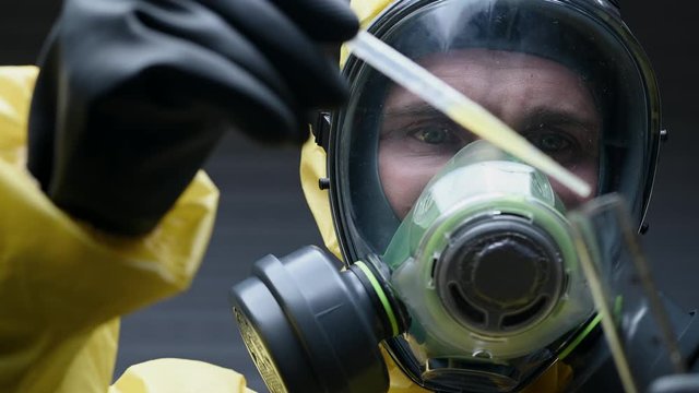 Chemist In Hazmat Suit Attentively Pours Serum Into Sample Tube. 