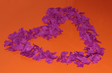 Purple heart on an orange background. A heart made of pieces of paper.