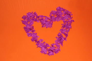 Purple heart on an orange background. A heart made of pieces of paper.