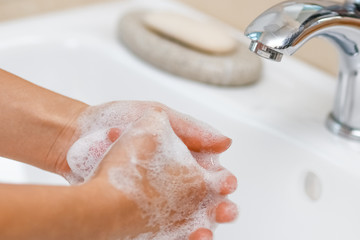 a Washing hands with soap under the faucet with water
