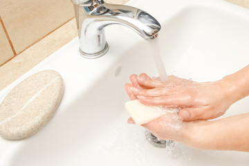 a Washing hands with soap under the faucet with water