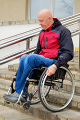 Fototapeta na wymiar man in a wheelchair independently descends a steep staircase with steel railings, active rehabilitation of disabled people, barrier-free 