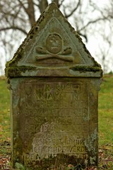 Grabstein mit Totenkopf an der Kirchenruine in Alt-Rhoden