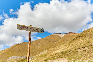 a sign of a guest house in the background of the mountains