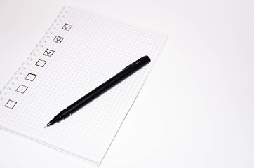 Check list. Square items are empty and checked with a tick. Squared notebook with black pen on a white background. Record ideas, notes, plans, tasks.  Copy Space