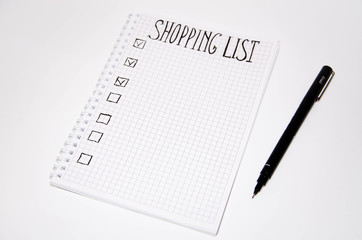 Shopping list. Squared notebook with black pen on a white background. Record ideas, notes, plans, tasks. The list includes bread, milk, bananas.  Copy Spase