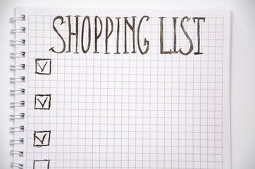 Shopping list. Squared notebook with black pen on a white background. Record ideas, notes, plans, tasks. The list includes bread, milk, bananas.  Copy Spase