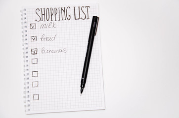 Shopping list. Squared notebook with black pen on a white background. Record ideas, notes, plans, tasks. The list includes bread, milk, bananas.  Copy Spase