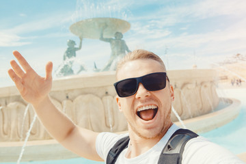 Valletta Malta happy tourist man in glasses makes selfie photo on background Triton fountain