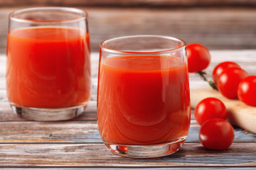 Two glasses of tomato juice on a wooden table, on a wood background, fresh drink