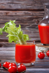 Glass of tomato juice on a wooden table, on a wood background, fresh drink