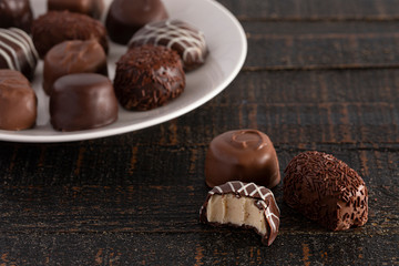 Assorted Chocolate Truffles on a Rustic Wooden Table in a Dark Environment