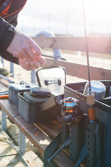 Fishing rod in the hands of a fisherman on the lake. Fisherman's hands with spinning on the background of water