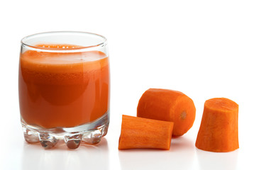 Freshly squeezed carrot juice in a glass and slices of peeled carrots isolated on a white background.