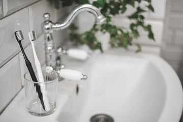 Two toothbrushes in a glass. Oral care. Personal hygiene items. Accessories in white bathroom. Copy space