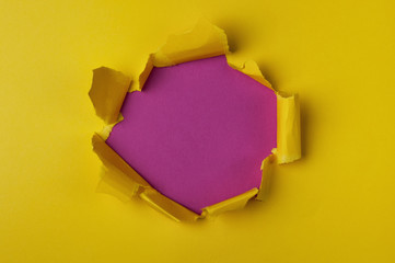 Bright yellow torn paper with pink purple hole. Abstract minimalistic background.