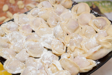 Dumplings, cooked at home, lie on a plate, sprinkled with flour.