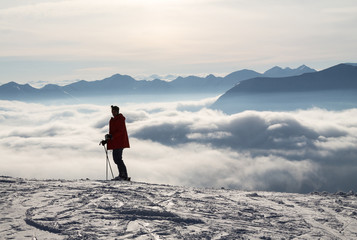 Skier on top of the snowy mountains, above the clouds, sunset sun. Caucasus mountains in winter, Georgia, Gudauri region.