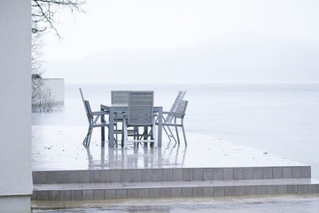 Wet British weather summer outdoor seat and table on decking in rain by lake at holiday home Loch Lomond