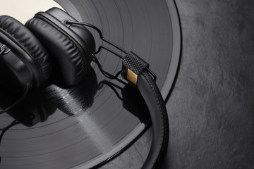 Over or on-ear headphones on vinyl record. - obrazy, fototapety, plakaty