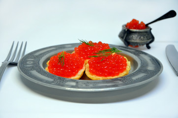 croutons with red caviar on a plate on white background 