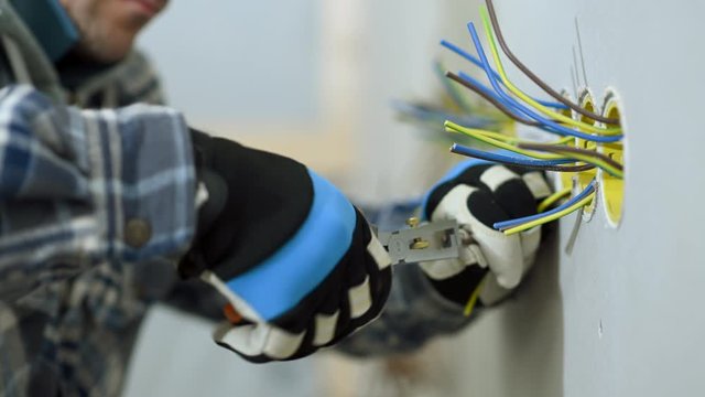 Electrician Cuts Wires In Outlet. He Prepares To Install Electric Plug. 