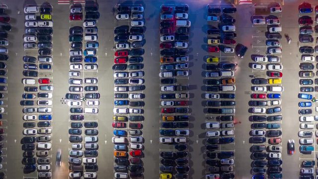 Aerial hyper lapse, top down view of supermarket (hypermarket or shopping mall) parking lot with a lots of cars at night. Time lapse