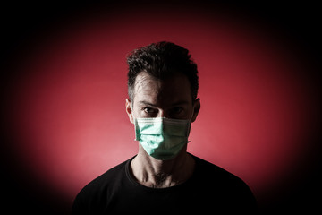 Portrait of  sick caucasian man with medical mask. Coronavirus Covid-19 concept. Red background 
