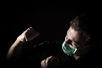 Portrait of  sick caucasian man with medical mask and punches. Coronavirus Covid-19 fight concept. Black background 