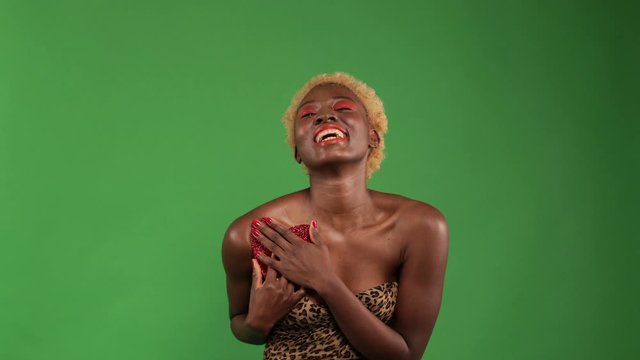 Young sexy african american woman smiling while spinning and holding a red paper heart in her hands, clutching it to herself, expressing the concept of love and friendship