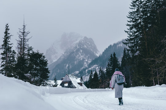 young girl in a coat and with a backpack in winter looks at the mountain. Ski resort vacation tourism. Hiking in a beautiful landscape. Tatra Mountains, Poland, Slovakia