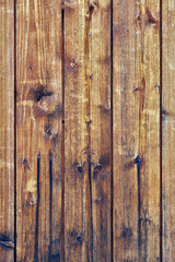 Background of wooden planks slats stacked vertically. The color is dark yellow, brown. Not painted old wooden surface, varnished. Drips of rust from nails. Vertical shot. Natural wood backdrop