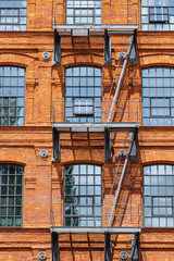Red brick classic industrial building facade with fire escape ladder stairs