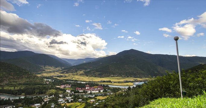 Time lapses at the kingdom of Bhutan, Motion Control Timelapse over the city of Paro with moving clouds in the evening before sunset. The Paro valley with the Rinpung Dzong. Panorama view in Bhutan