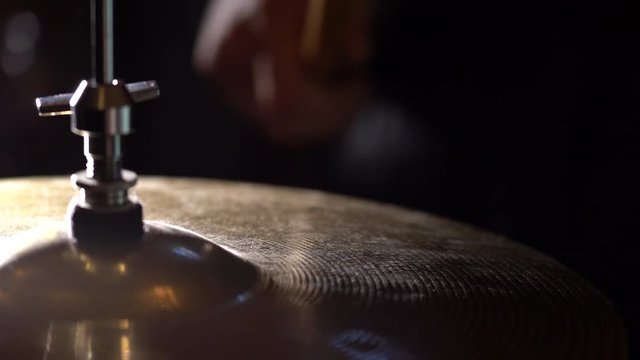 Hands of musician holds drum sticks hits on crash cymbal on dark background