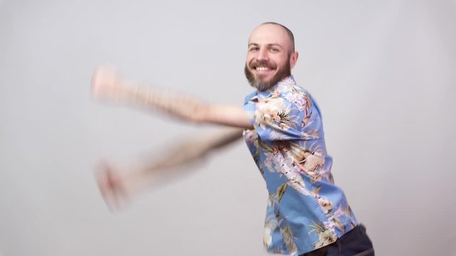 Funny dance of a man wearing hawaiian shirt. Cheerful bearded bald man dancing and having fun on white background.