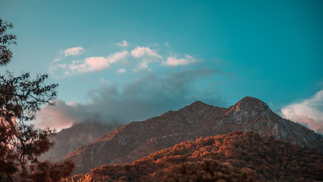 Mountains in the sunet, covered in clouds.