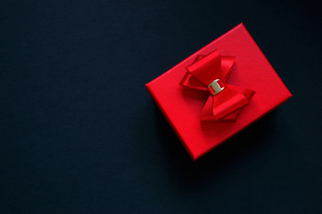 Red gift box with a red bow on a dark background