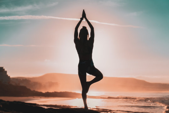 Woman doing yoga in the rising sun.