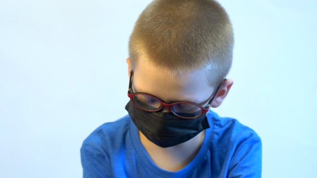 Cute blond boy in quarantine at home. baby in blue medical mask is struggling with illness, fever and strong cough. Epidemic control of coronavirus and proper infection prevention. Child coughs