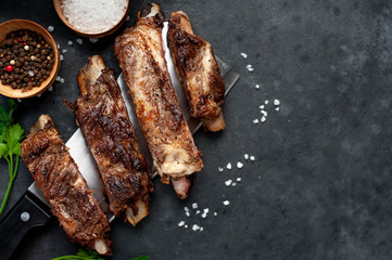 grilled pork ribs over meat knife with spices on a stone background