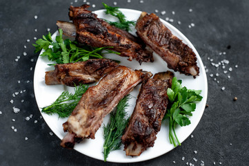 grilled pork ribs in a white plate with spices on a stone background