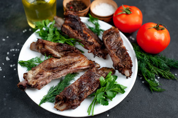 grilled pork ribs in a white plate with spices on a stone background