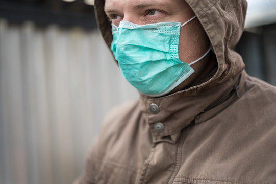 Nachdenklich und ernster Blick eines Mannes mit Mundschutz als Symbol für Infektionskrankheiten