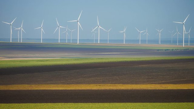 Many industrial wind turbines on agriculture field, sustainable energy future technology preserving the natural beautiful landscape environment